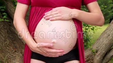怀着双手的孕妇拥<strong>抱</strong>、拥<strong>抱</strong>和抚摸他怀孕的腹部。 幸福的未来妈妈和父母正在等待<strong>宝宝</strong>。